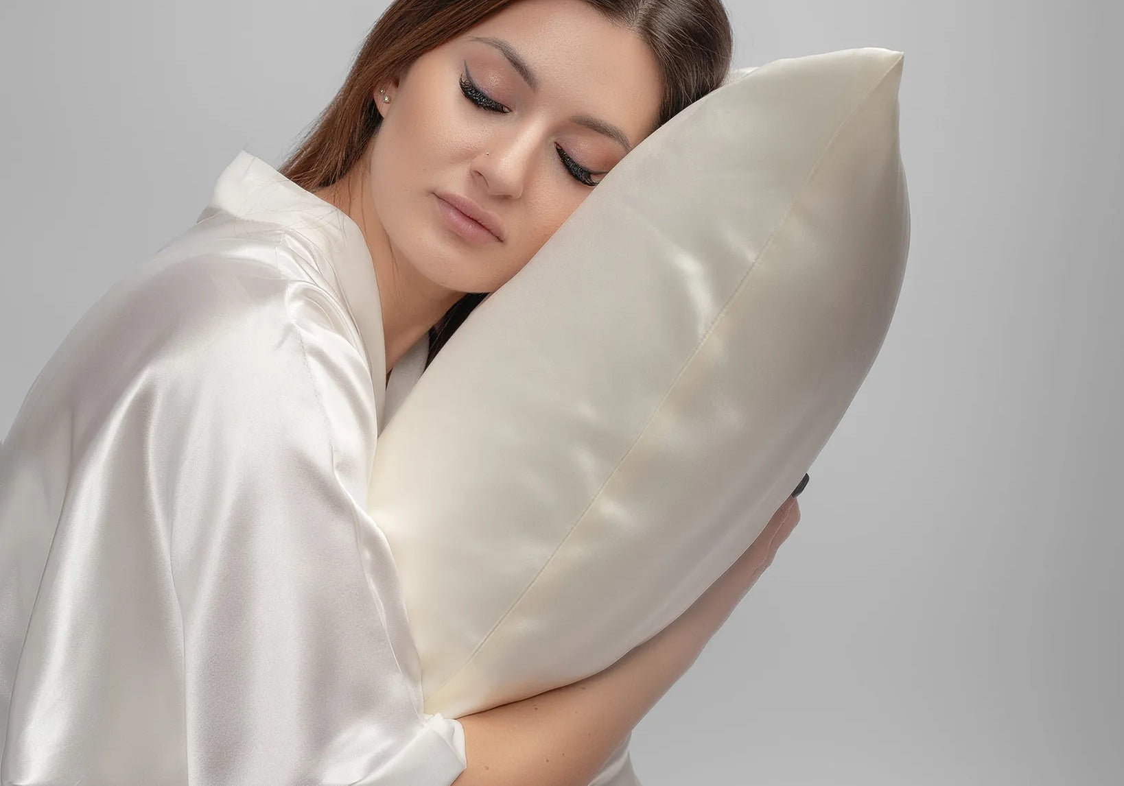 Woman in a silk robe resting peacefully against a silk pillow for sensitive skin