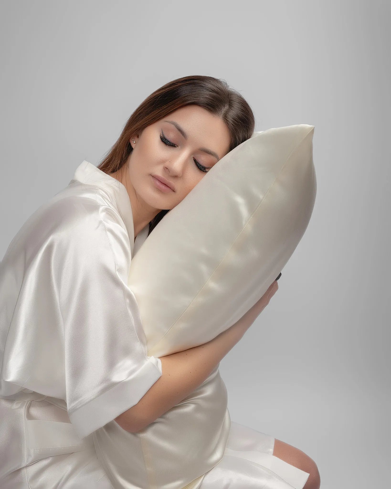 Woman in a silk robe resting peacefully against a silk pillow for sensitive skin