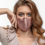 Dusty pink silk face mask with nose wire by Mulberry, shown on a person with wavy auburn hair and lace-trimmed top.