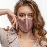 Dusty pink silk face mask with nose wire by Mulberry, shown on a person with wavy auburn hair and lace-trimmed top.